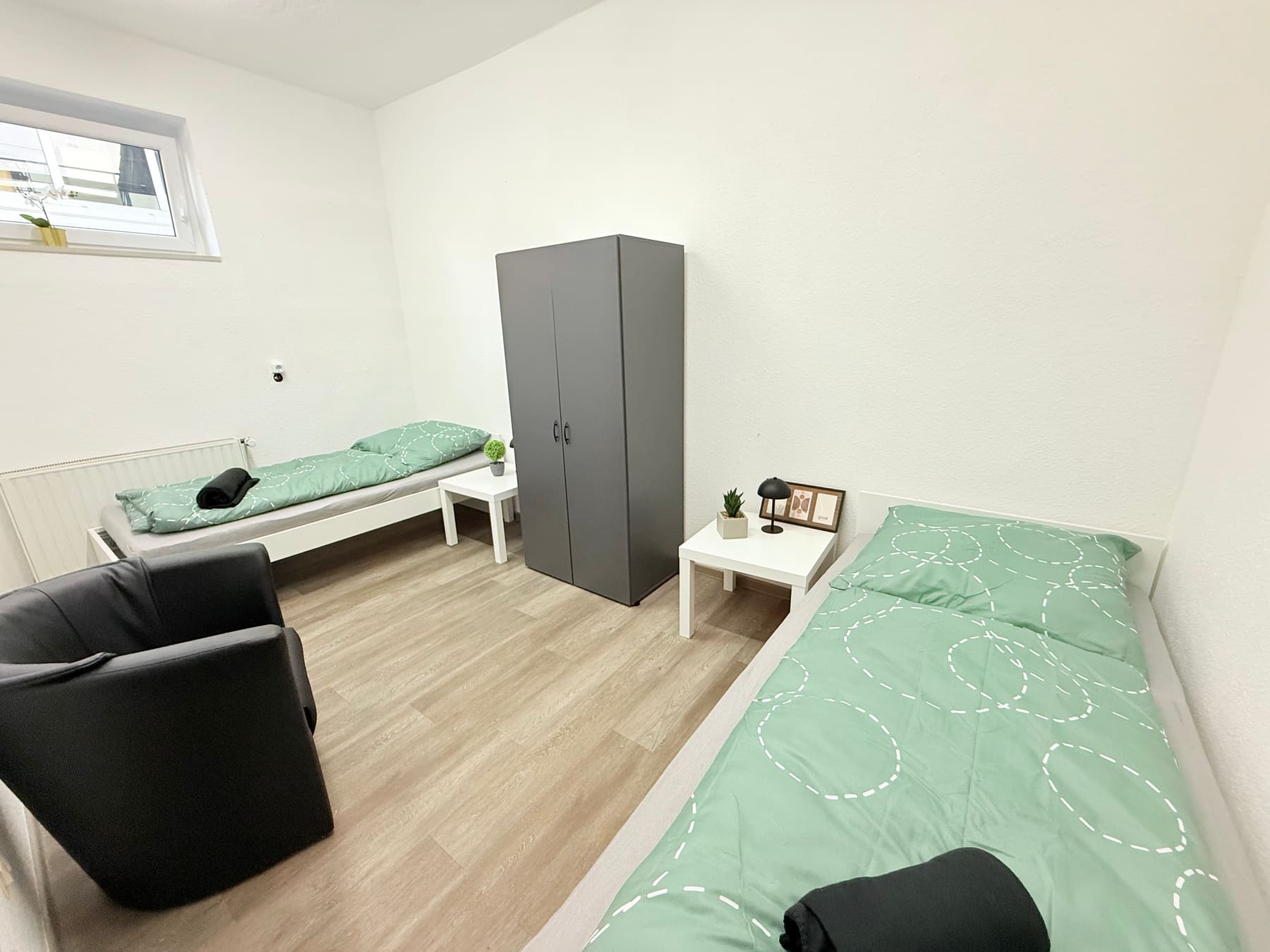 Schlafzimmer mit zwei Einzelbetten, Schrank und Sessel